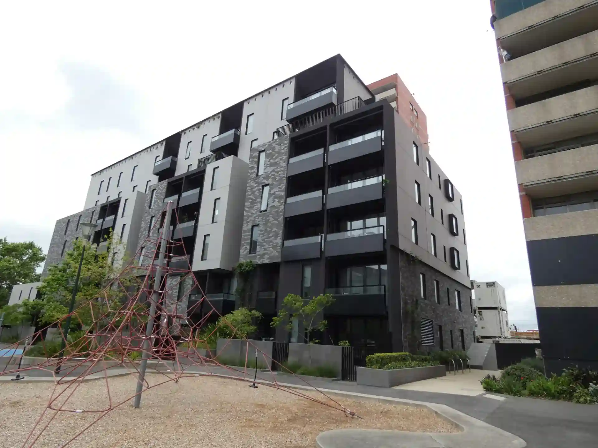 Modern apartment building with balconies and a playground in the foreground